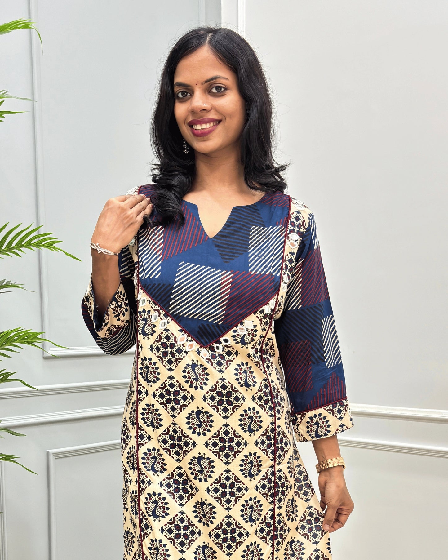Close-up of Beige women's Vegetable dyed cotton long-kurti featured with V-shaped neck & yoke on front , hand-mirror wok on yoke border& sleeves calf.