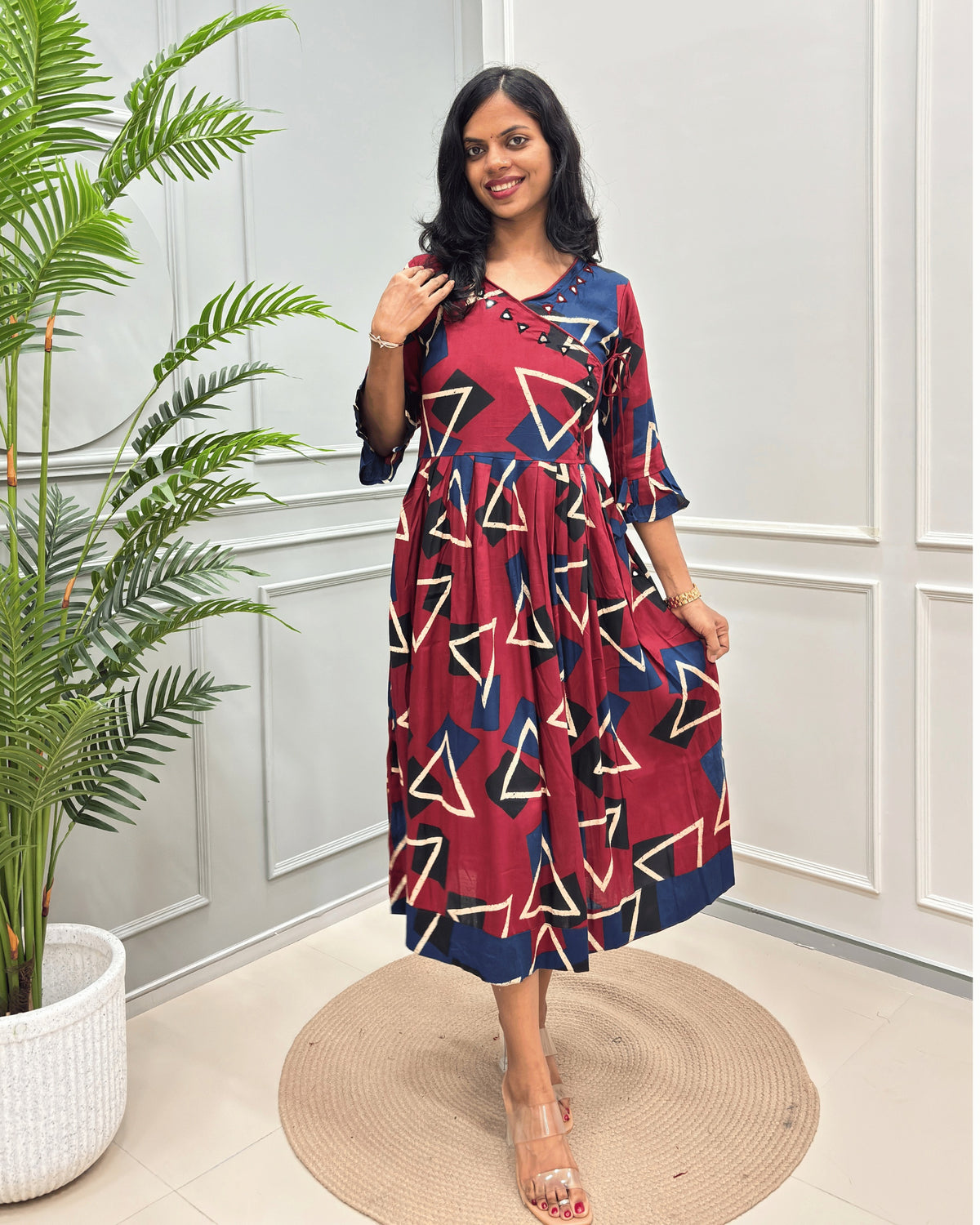 Red women's vegetable dyed rayon cotton Long-kurti featured with Ajrakh print and Angrakha pattern with lace. standing in front of white wall.