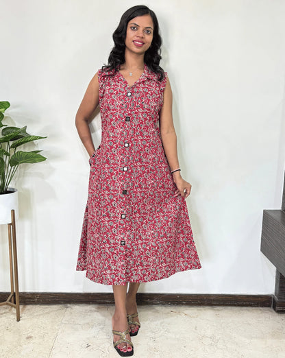 Red Women Ajrakh Vegetable dyed plant based cotton Long Kurti with a Black, & white abstract print, Standing against a white wall with a plant to her left.