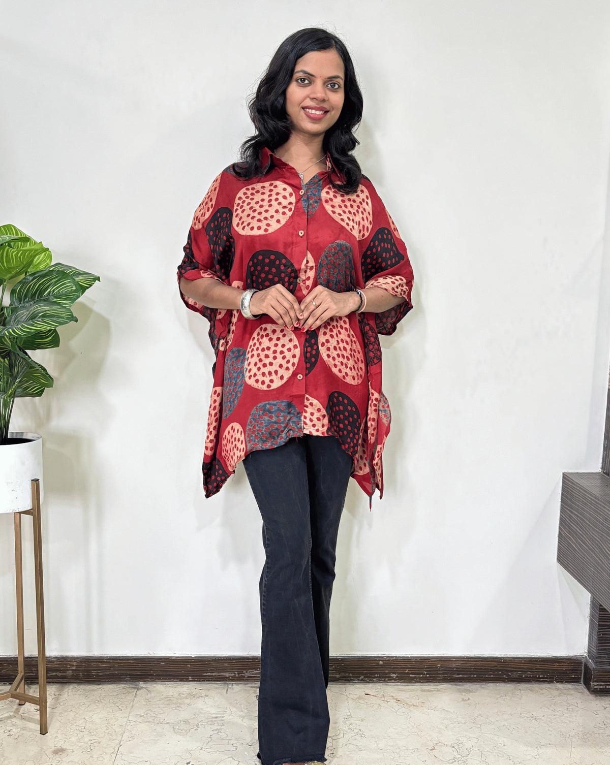 Red Women's Ajrakh pure Mashru Silk Short Kaftan Shirt with a bold abstract of pink, black, and red geometric circles print, paired with dark pants, standing in front of a white wall.