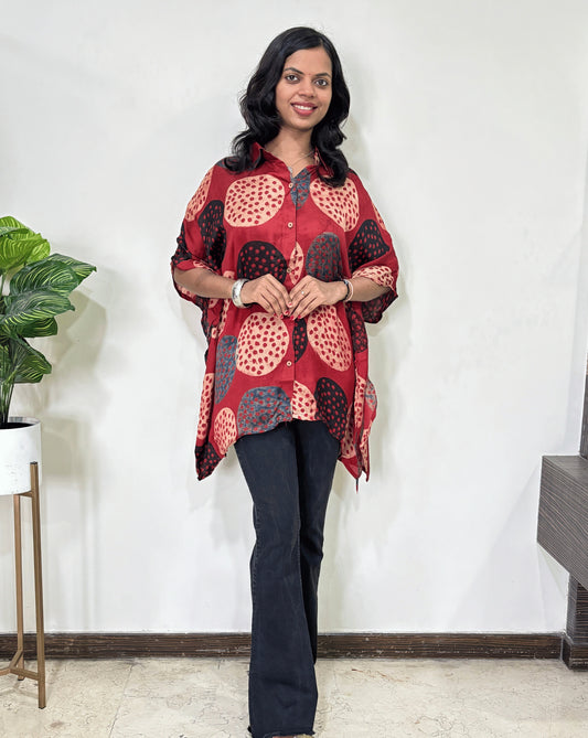 Red Women's Ajrakh pure Mashru Silk Short Kaftan Shirt with a bold abstract of pink, black, and red geometric circles print, paired with dark pants, standing in front of a white wall.