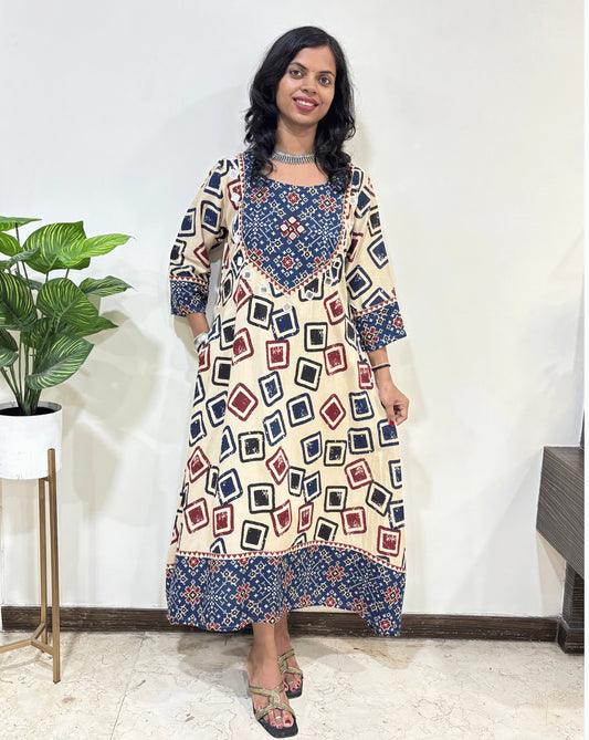 Beige Women's Ajrakh Vegetable dyed plant based cotton One-peice with beautiful patola print yoke on front, bottom & Sleeves cuffs, Standing in front of White wall.