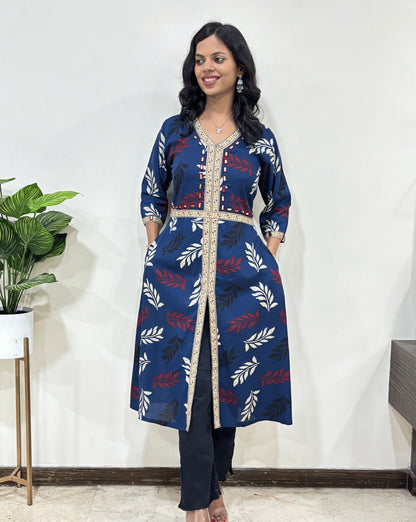 Front view of Beige Woman's Ajrakh Vegetable dyed Planet based cotton Long-kurti with a leaf print along with Ajrakh print on border from V-shaped neck on front & Sleeves cuffs with Middle Slit, 2-side pockets, standing indoors with a plant and white wall in the background.