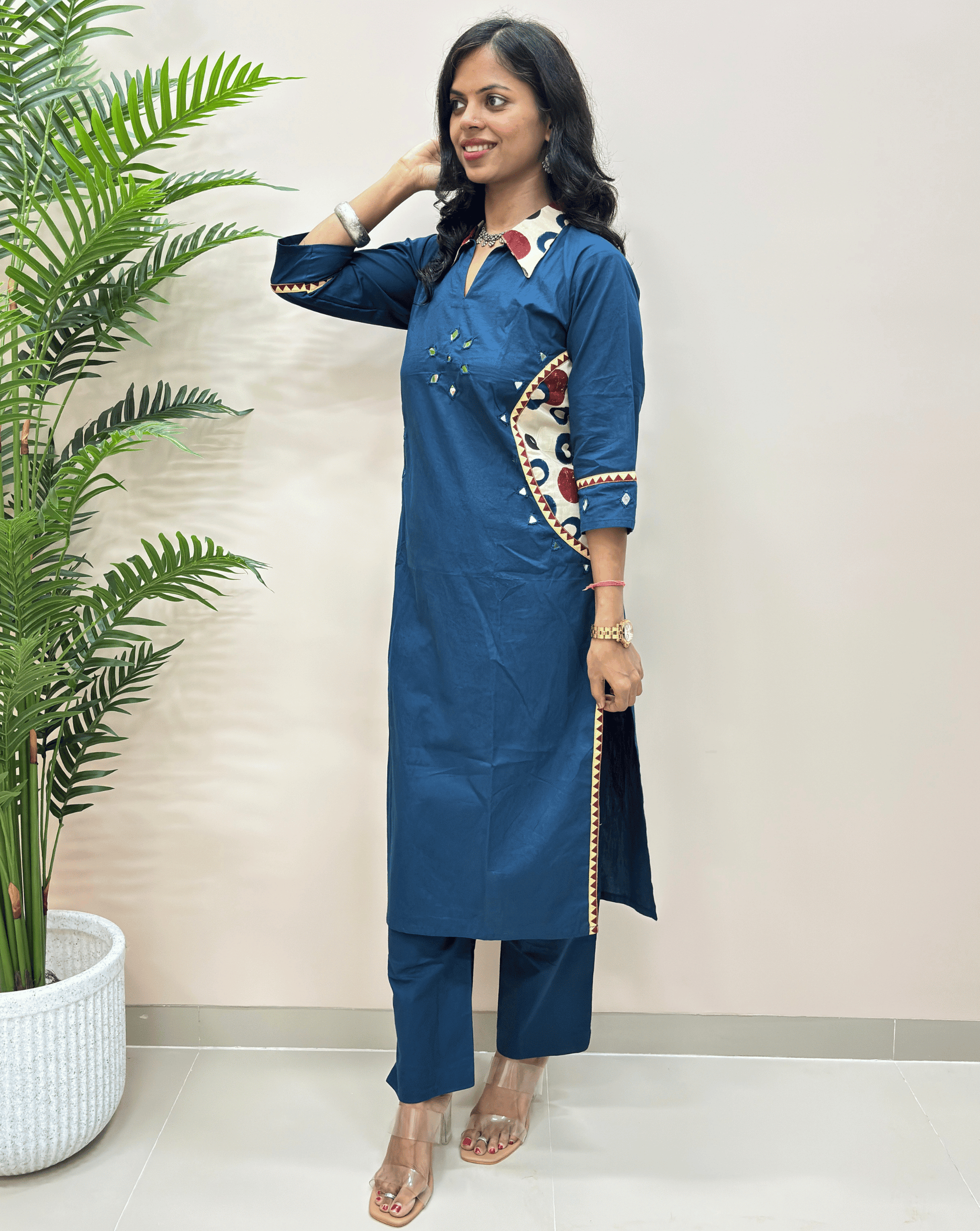  Blue women's ajrakh vegetable dyed cotton Co-ord set side view  with matching pants, featuring a white collar and colorful embroidered details on the sleeve and side pocket style, standing next to a potted plant.