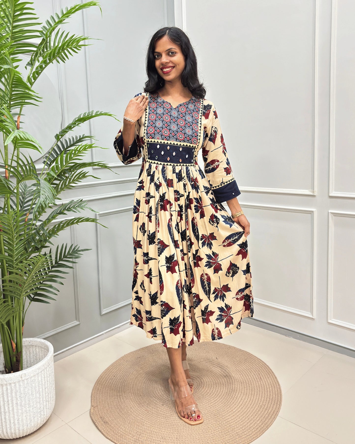 Beige Women's Ajrakh vegetable dyed Rayon Cotton Long-kurti with Three-quarter Sleeves , colorful geometric print on neck and ajrakh border print on front & sleeves , standing in front of grey wall.
