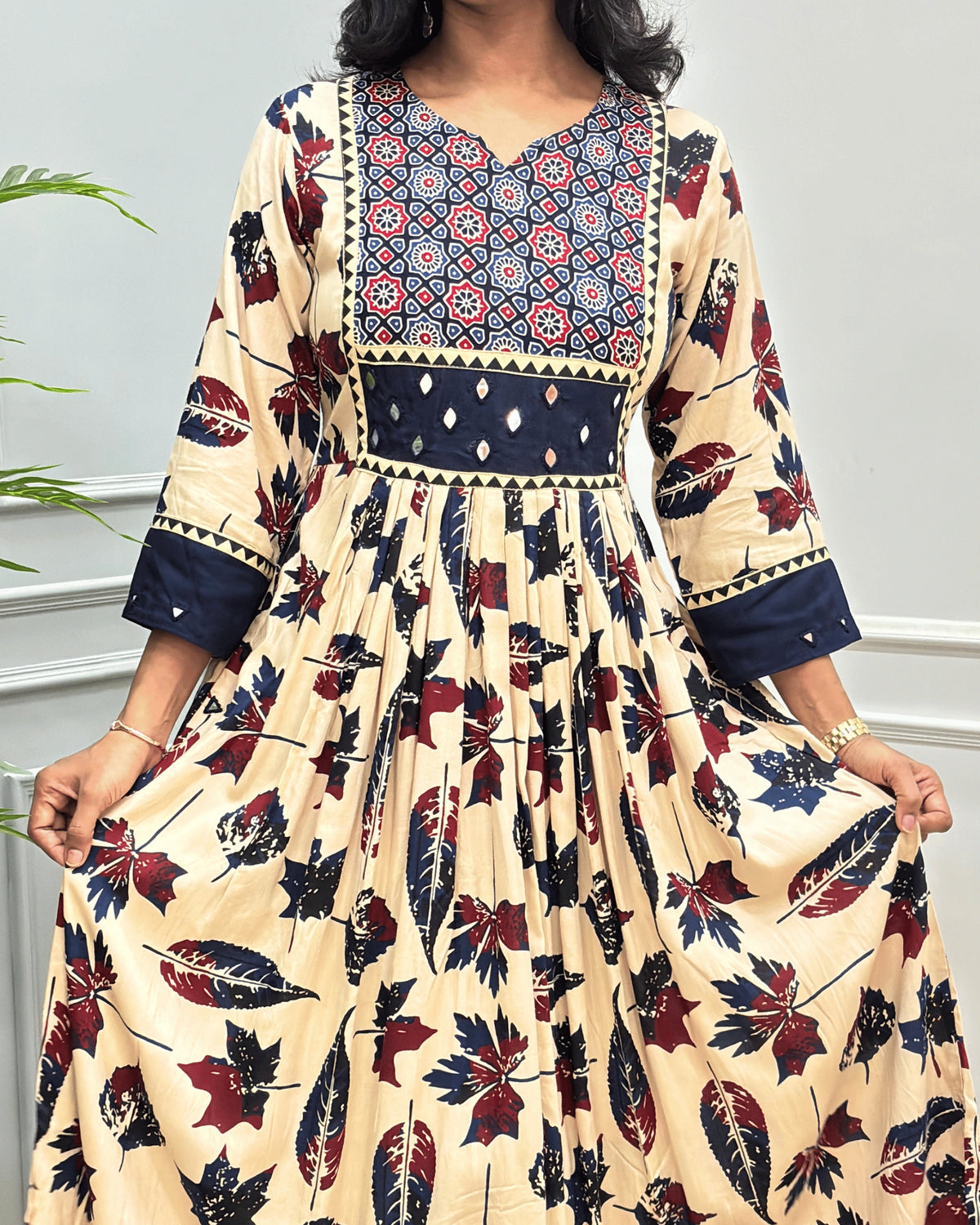 Close-up of Beige Ajrakh Plant based cotton Long-kurti featured with three-quarter sleeves , geometric print on neck-line , hand-mirror work on front chest & sleeves cuffs, Beautiful leaf print in dress., curved V-neck pattern 