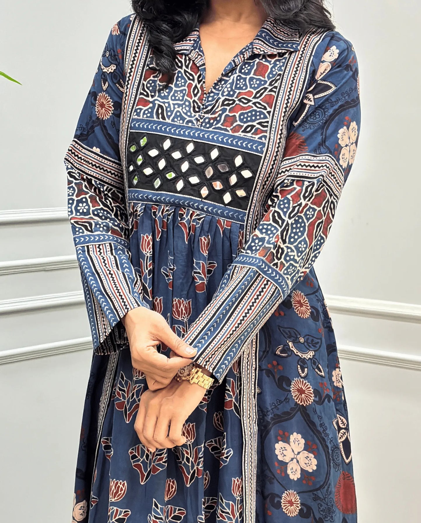 Close-up of handcrafted mirror work on blue Ajrakh cotton long-kurti dress with Ajrakh printed sleeves detail on dress. mirror work on chest. 
 