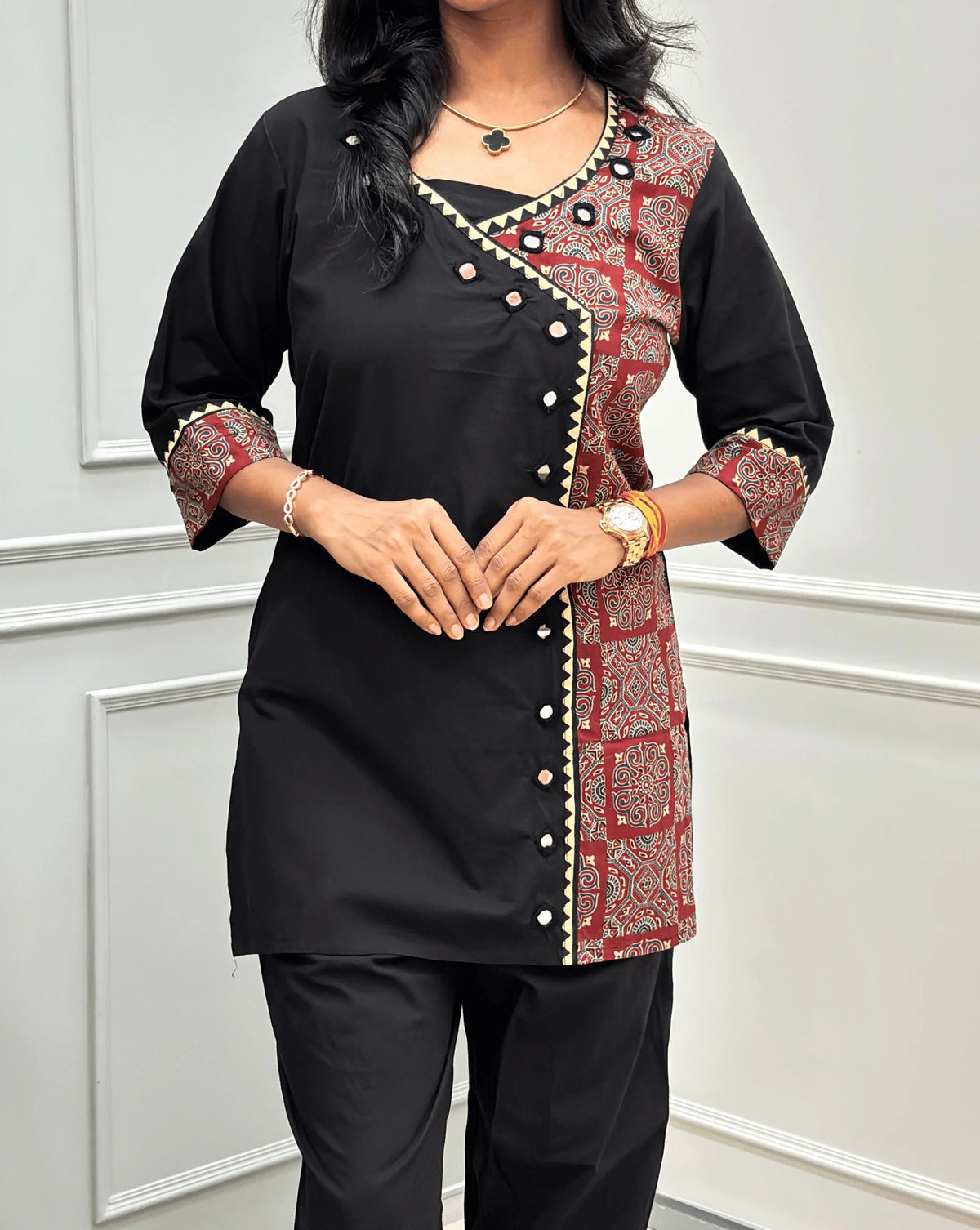 Close-up view of Blue Women's Ajrakh Pure Cotton 2-peice Co-Ord set Featured with V-shaped neck with a Ajrakh printed panel on the front & Sleeves, Angrakha Patterned on front, Real Hand-Mirror work on front Along with 2 side pockets in pant, standing on a round woven rug in a modern room with white paneled walls.