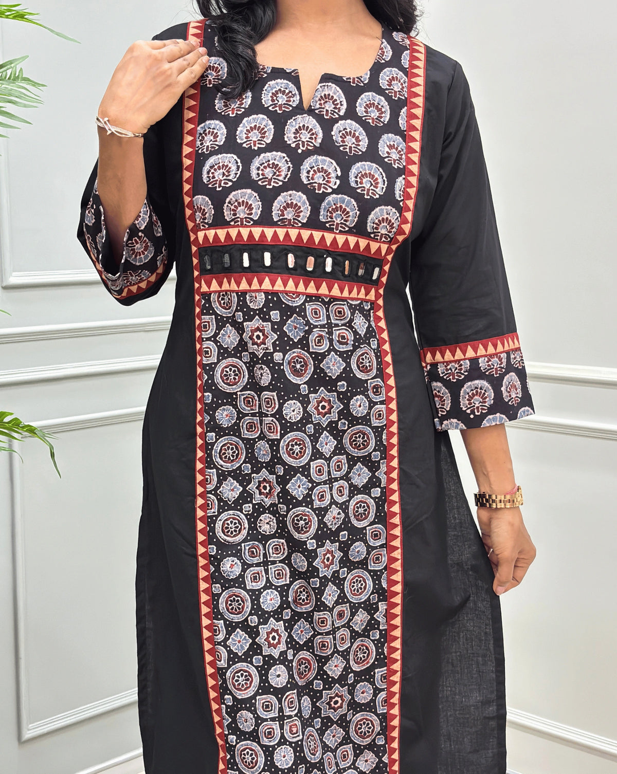 Close-up of Black Ajrakh Hand-block cotton long-kurti featuring hand-mirror work on front like a belt, geometric print below the mirror work in panel , V-shaped round neck-line.