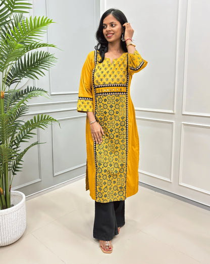 Mustard Yellow women's ajrakh vegetable dyed long-kurti with floral print on upper side and sleeves cuffs, triangle shaped border-line on front and sleeves, paired with Black Flared jeans.