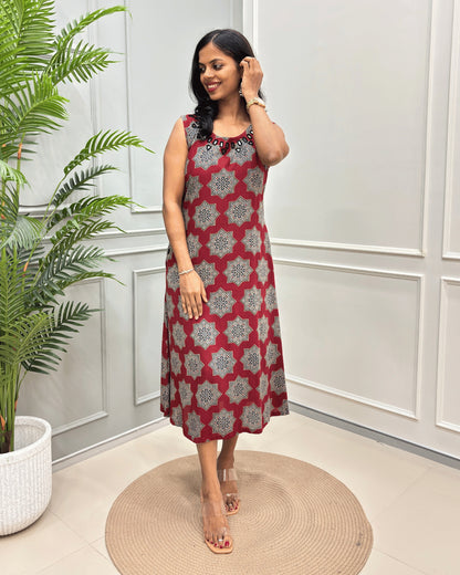 Red Women's Plant based Cotton Long sleeveless Kurti with a Beige & black geometric floral pattern, standing on a round woven rug in front of a white paneled wall with a potted plant.