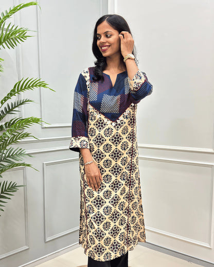 front side view of Beige cotton long kurti with Hand-mirror work on V-shaped yoke on front and sleeves, red colour pie-pin on front , peacock print on Beige base .
