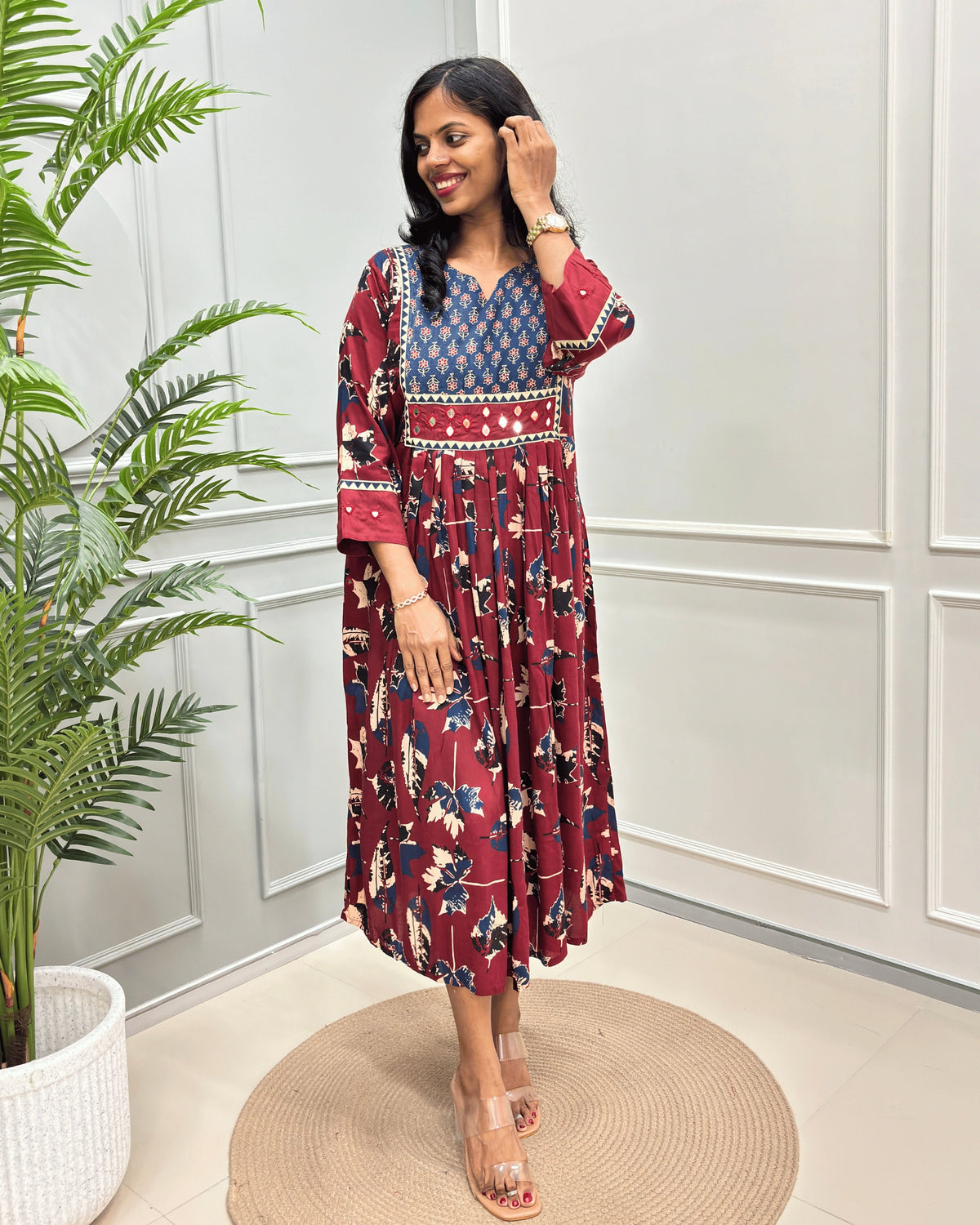 Red Women's Ajrakh vegetable dyed Rayon Cotton Long-kurti with Three-quarter Sleeves , colorful geometric print on neck and ajrakh border print on front & sleeves , standing in front of grey wall.