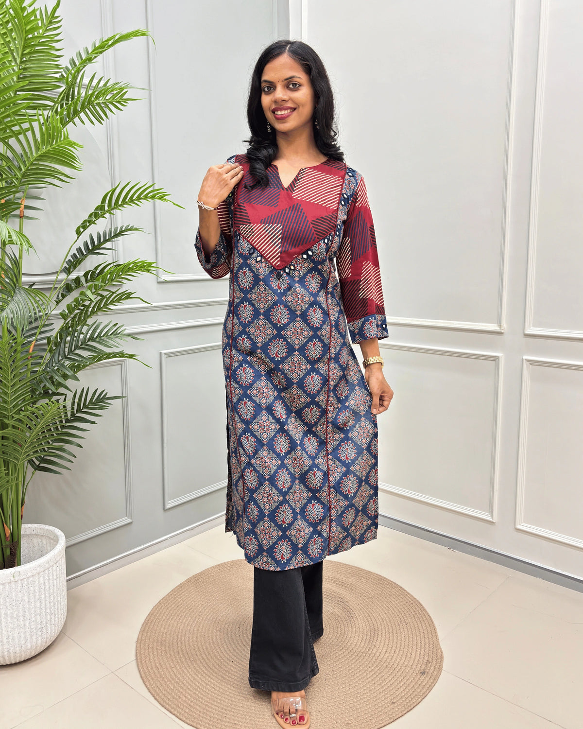 Blue Women's Vegetable dyed plant based cotton Straight Long-kurti featured strip print on red base on front and half sleeves with peacock print from top-bottom on sleeves, standing in front of white wall and a potted plant .