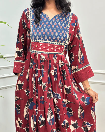 Close-up of Red Ajrakh Plant based cotton Long-kurti featured with three-quarter sleeves , floral print on curved V-neck-line , hand-mirror work on front chest & sleeves cuffs, Beautiful leaf print on dress along with pocket.