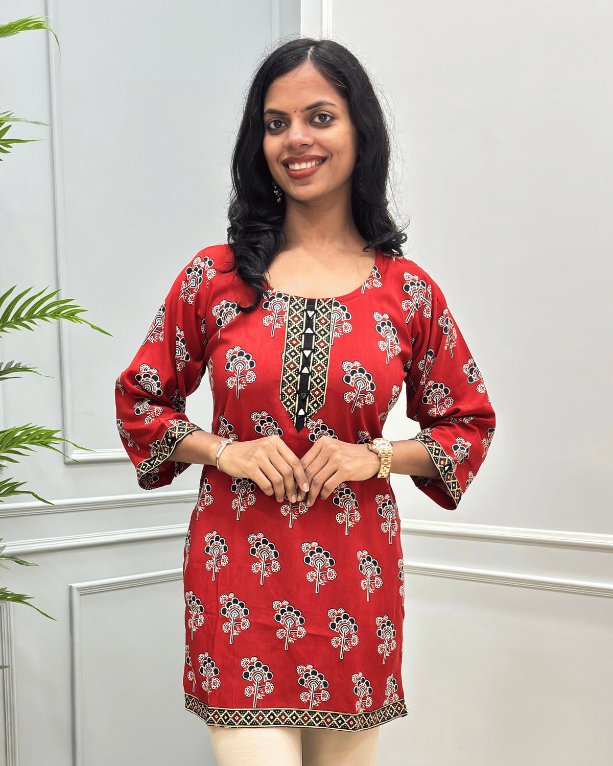 Close-up of Red women's cotton Short kurti featuring a Floral printed patterned with ajrakh print on neckline, bottom, sleeves cuffs, hand-mirror work on Round-neck .