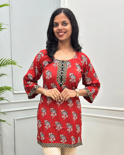Close-up of Red women's cotton Short kurti featuring a Floral printed patterned with ajrakh print on neckline, bottom, sleeves cuffs, hand-mirror work on Round-neck .