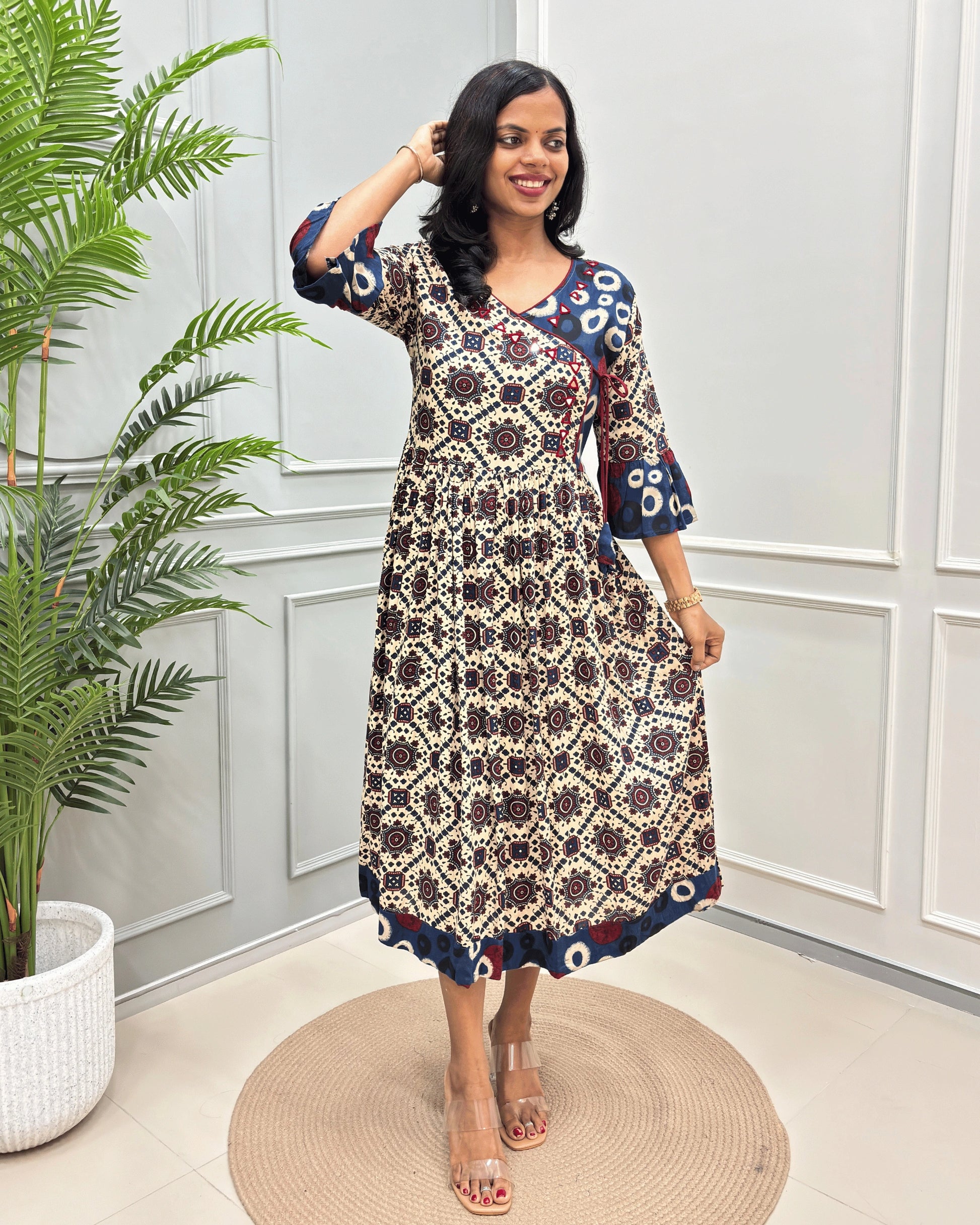 Beige women's vegetable dyed rayon cotton Long-kurti featured with Ajrakh print and Angrakha pattern with lace. standing in front of white wall.