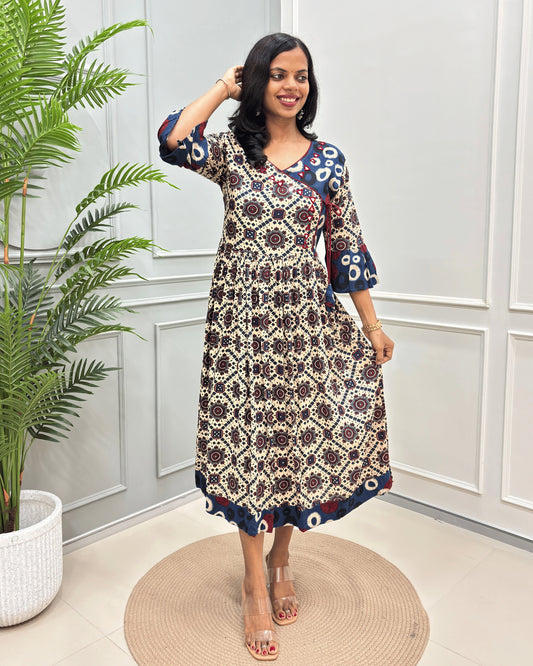Beige women's vegetable dyed rayon cotton Long-kurti featured with Ajrakh print and Angrakha pattern with lace. standing in front of white wall.