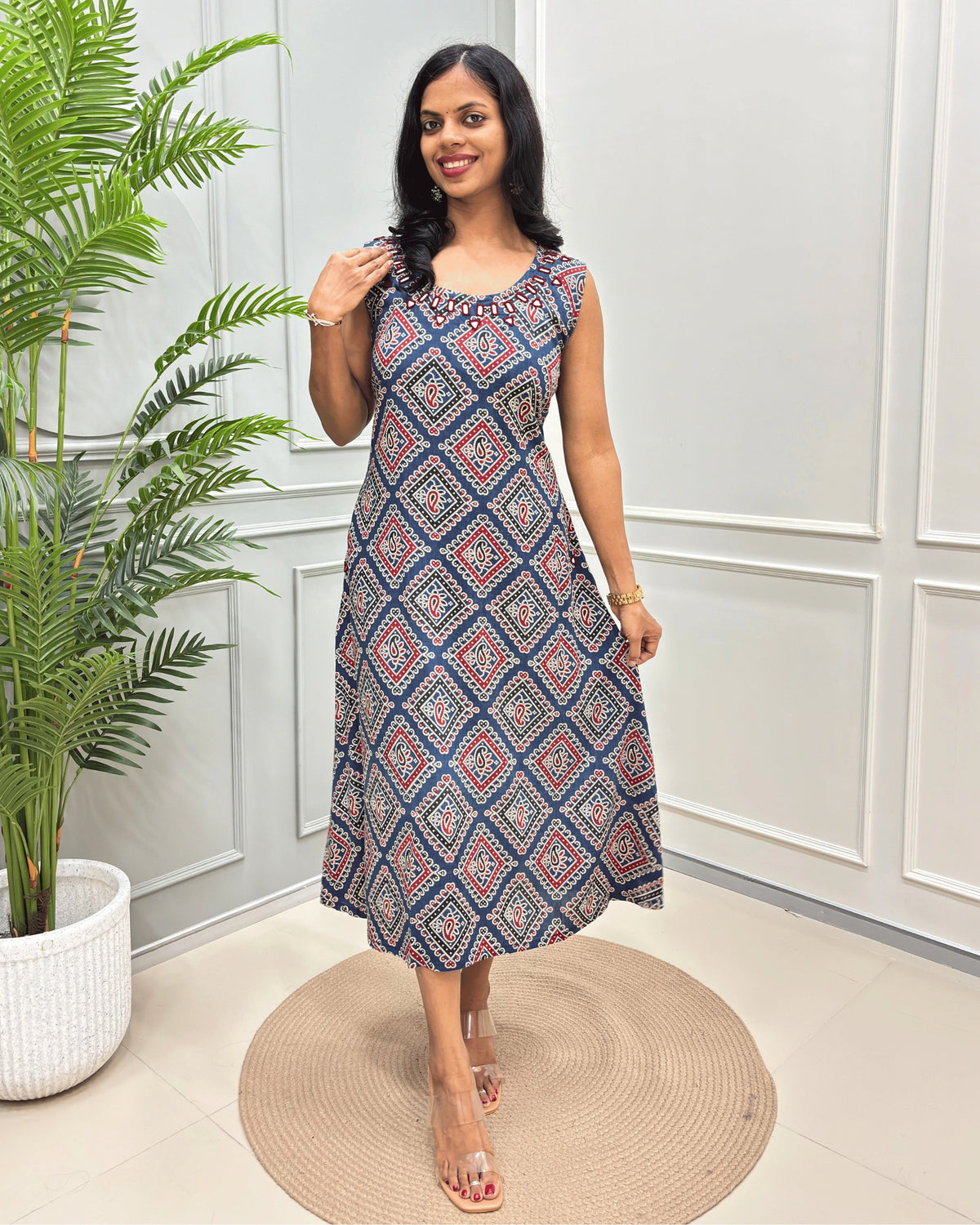 Blue Women's Vegetable dyed plant based cotton Long sleeveless Kurti with a Colorful geometric diamond pattern , standing on a round woven rug in front of a white paneled wall with a potted plant.
