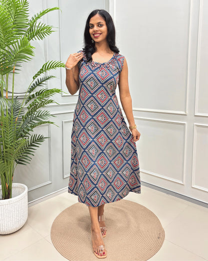Blue Women's Vegetable dyed plant based cotton Long sleeveless Kurti with a Colorful geometric diamond pattern , standing on a round woven rug in front of a white paneled wall with a potted plant.