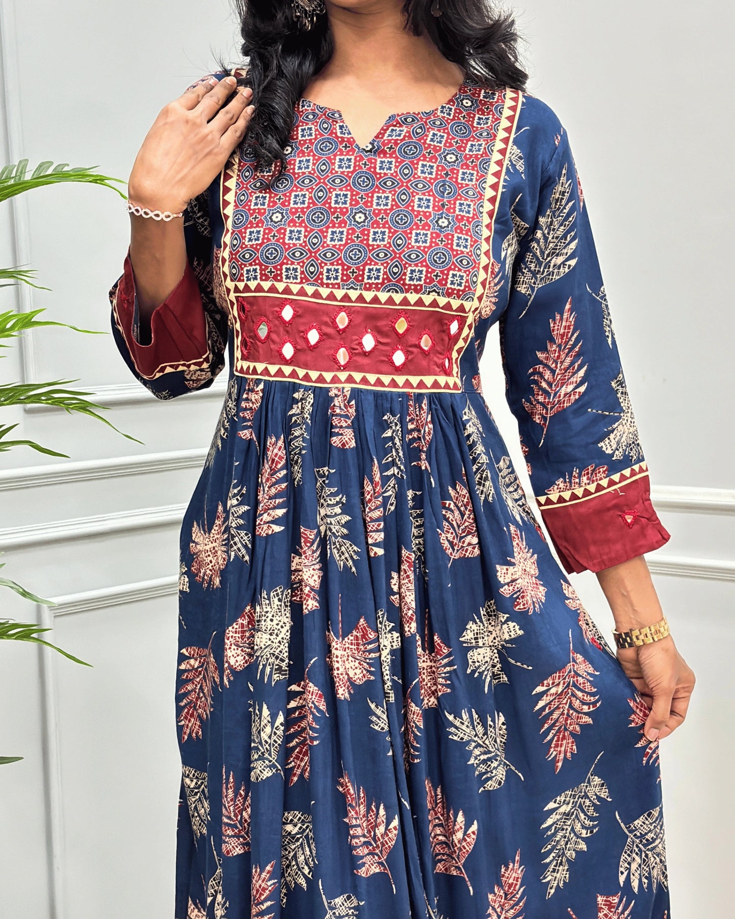 Close-up of Blue Ajrakh Plant based cotton Long-kurti featured with three-quarter sleeves , floral print on Geometric V-neck-line , hand-mirror work on front chest & sleeves cuffs, Beautiful leaf print on dress along with pocket.