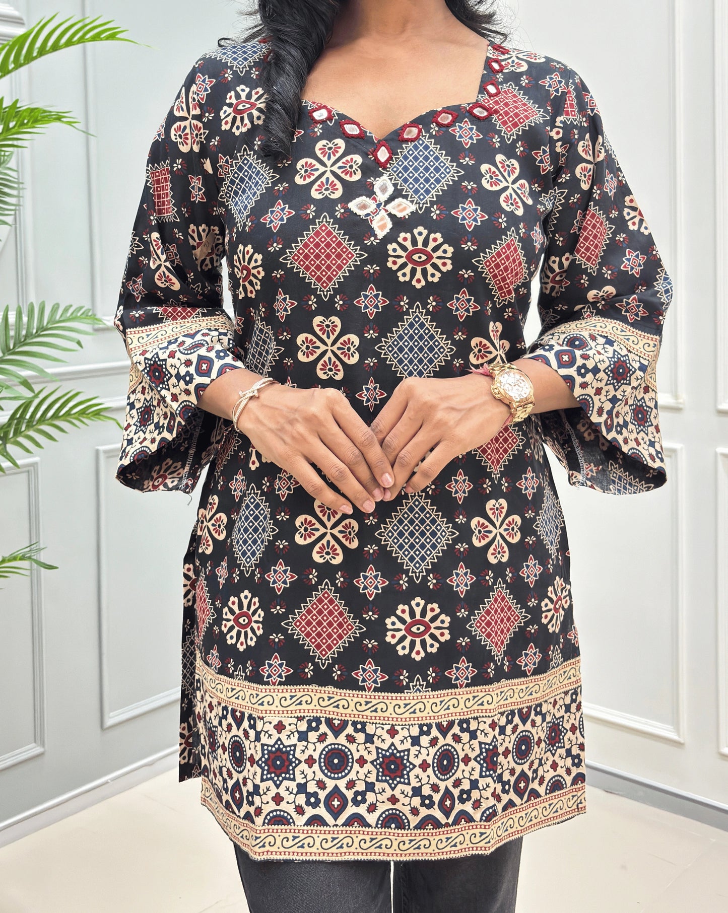Close-up of Short kurti with mirror work on Black Ajrakh cotton kurti colourful geometric & floral motifs, Ajrakh printed detail on black cotton kurti , featuring a bell sleeves & a decorative border hems