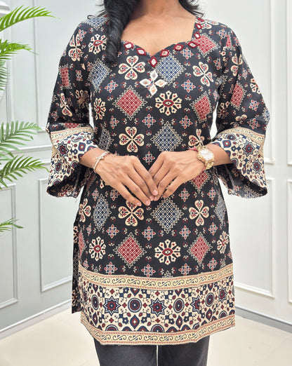 Close-up of Short kurti with mirror work on Black Ajrakh cotton kurti colourful geometric & floral motifs, Ajrakh printed detail on black cotton kurti , featuring a bell sleeves & a decorative border hems