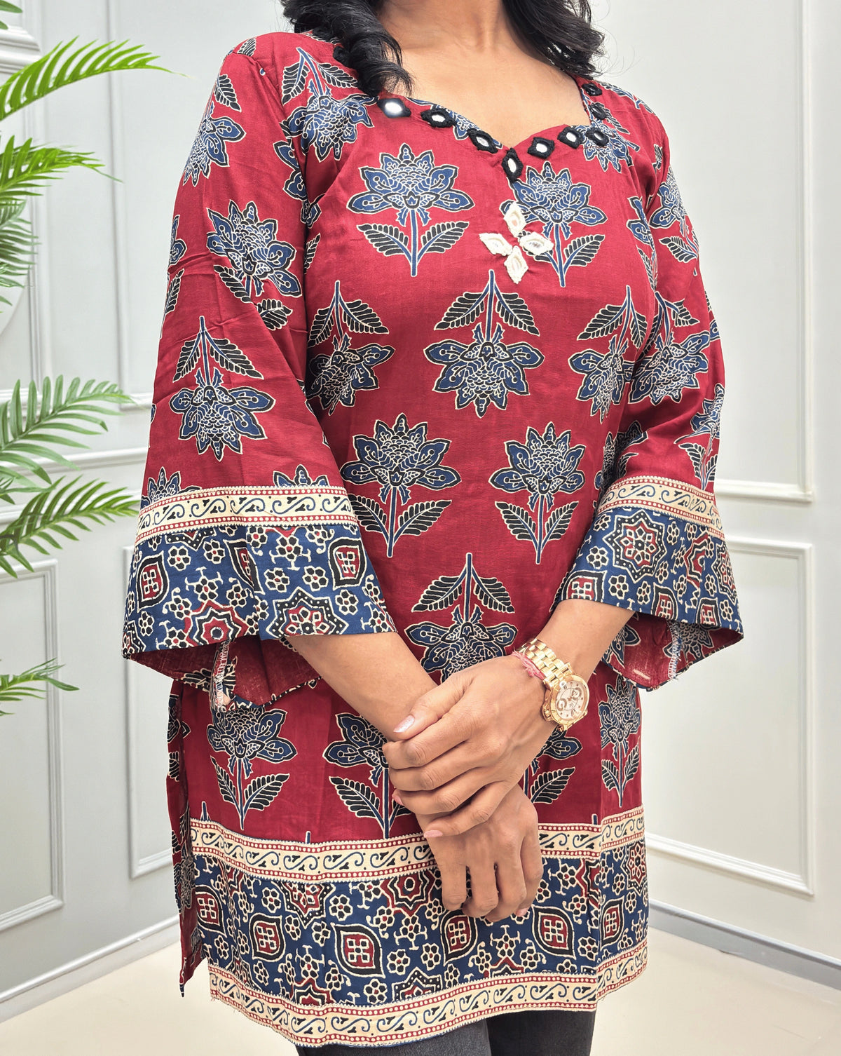 Side view of Red short cotton Ajrakh kurti featuring a detail three-quarter sleeves & decorative Ajrakh print border, hand-mirror work at neck-line & chest.