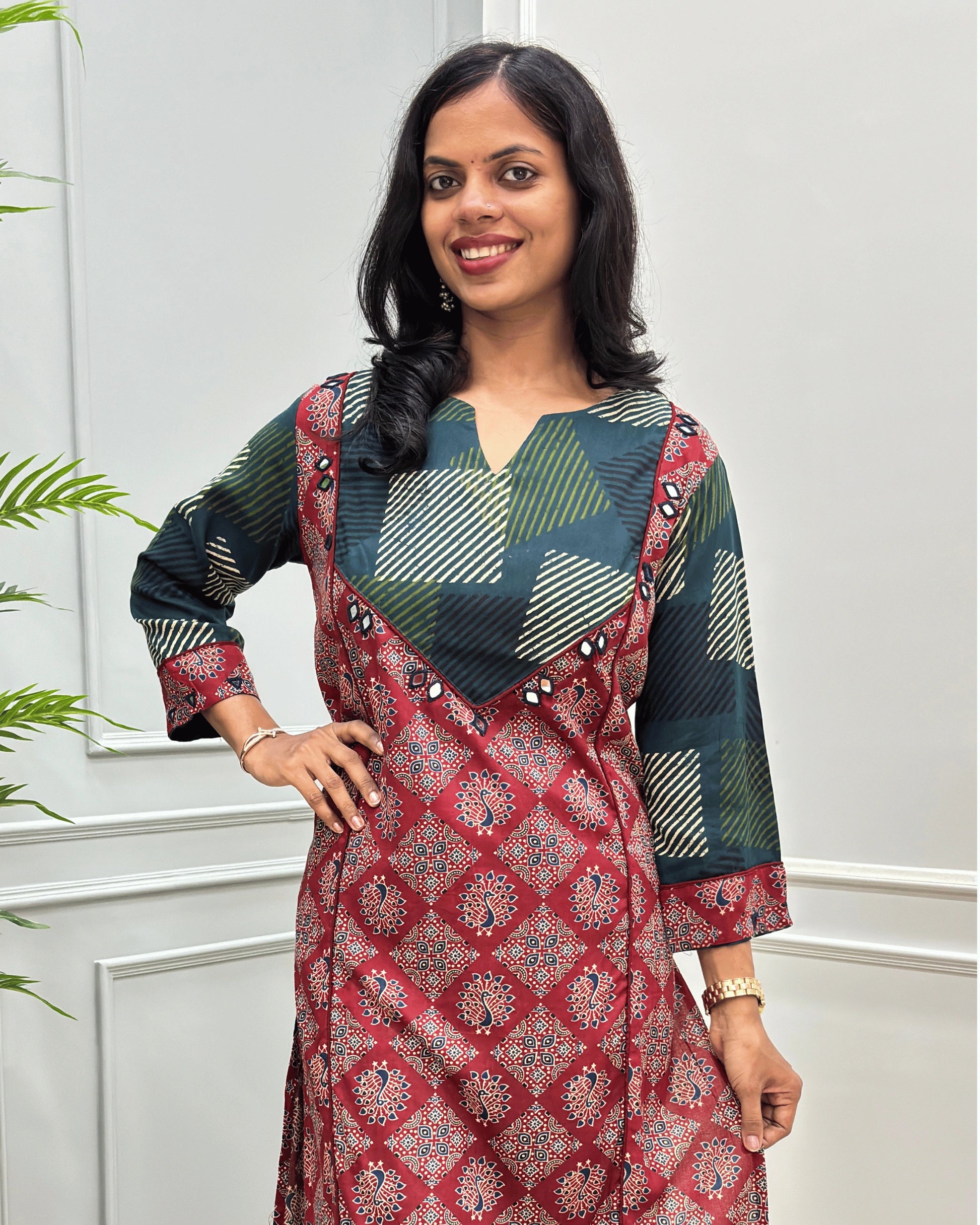 Close-up of Red women's Vegetable dyed cotton long-kurti featured with V-shaped neck & yoke on front , hand-mirror wok on yoke border& sleeves calf.