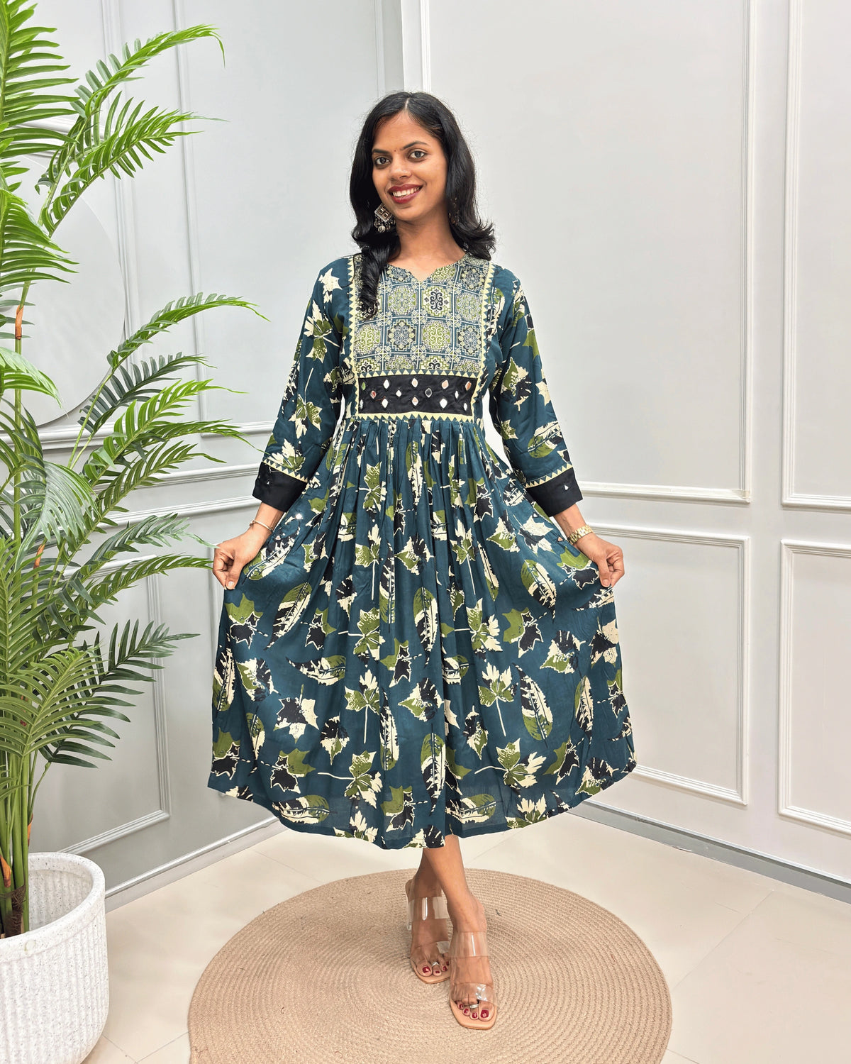 Green Women's Ajrakh vegetable dyed Rayon Cotton Long-kurti with Three-quarter Sleeves , Ajrakh print on neck Geometric  border print on front & sleeves , standing in front of grey wall.