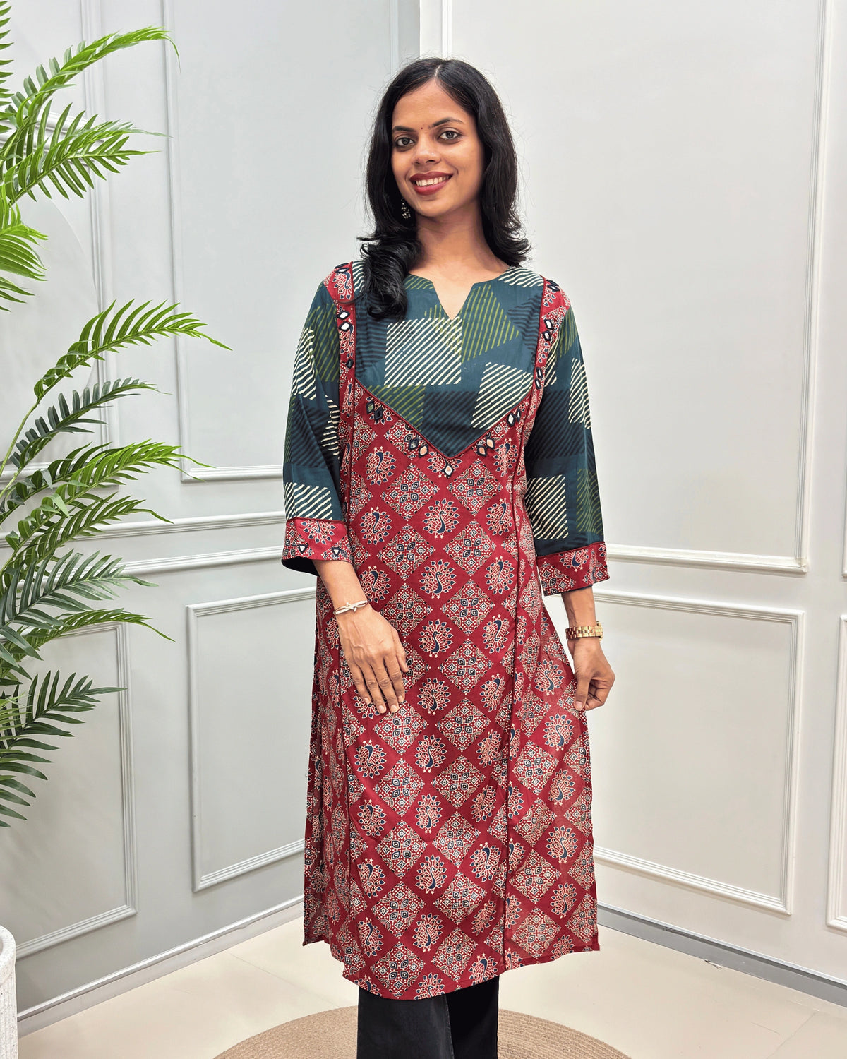 front side view of Red cotton long kurti with Hand-mirror work on V-shaped yoke on front and sleeves, red colour pie-pin on front , peacock print on Red base .