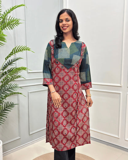 front side view of Red cotton long kurti with Hand-mirror work on V-shaped yoke on front and sleeves, red colour pie-pin on front , peacock print on Red base .