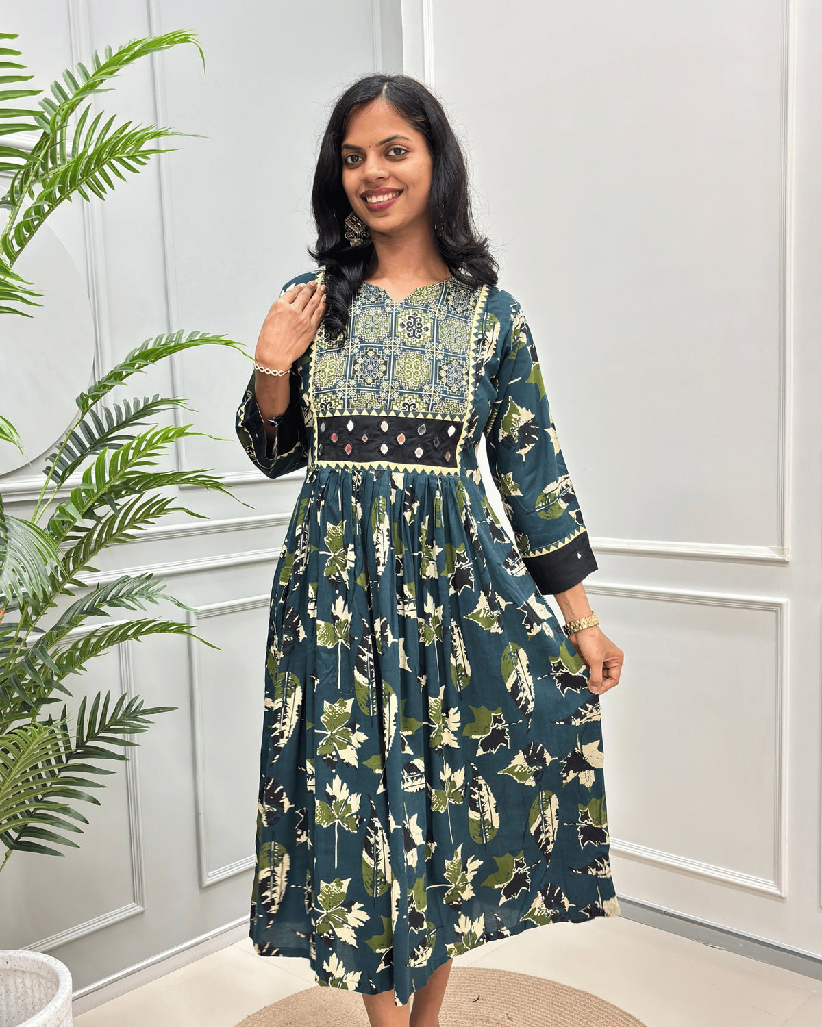 Front view of Green women's Ajrakh plant based Cotton Long Kurti featured with Ajrakh print on green base on Curved V-neck, Hand-mirror wok on front & Sleeves cuffs. leaf print with abstract green, black & beige .
